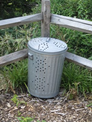 Tin compost bin in front of fence